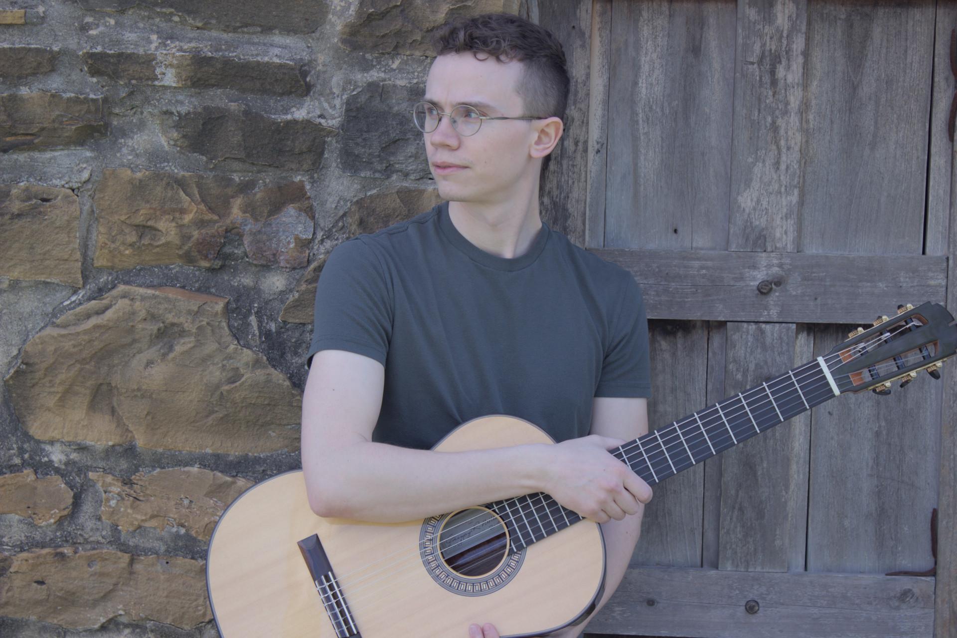 Chris Stevens Looking into the Distance While Holding a Guitar